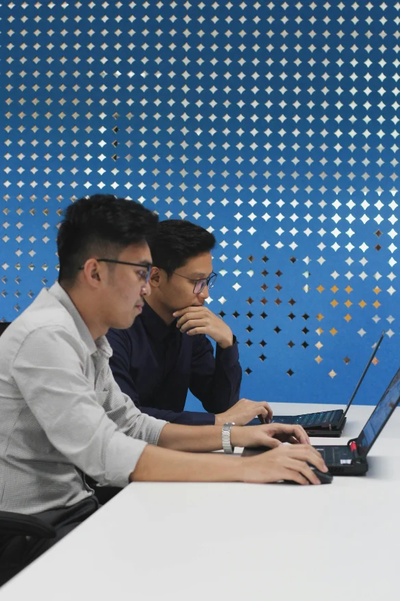 Two engineers working side by side at laptops